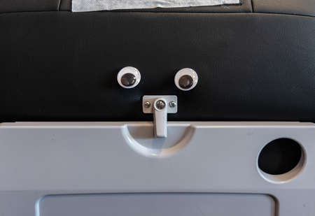Googly eyes on the back of a airplane seat.の写真素材