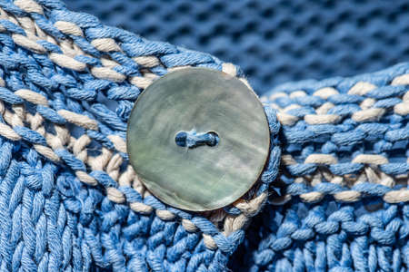 A button on a blue knitted sweater.
