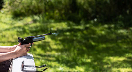Gas coming out of the muzzle of a BB air pistol. The bullet can be seen in front of the gun.