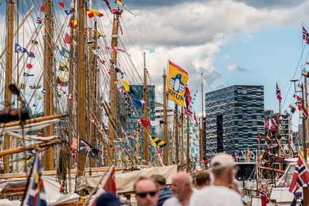 Oslo, Norway - July 19 2014: Masts and rigging of wooden sail boats in front of modern office buildings.のeditorial素材