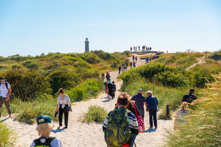 Skagen, Denmark - July 10 2019: Tourists on walking paths leading to Grenen with the Grå Fyr in the background.のeditorial素材