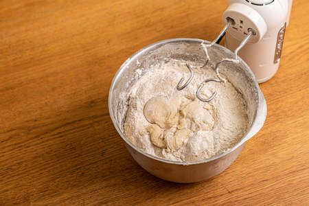 Hand mixer and a metal bowl with dough.