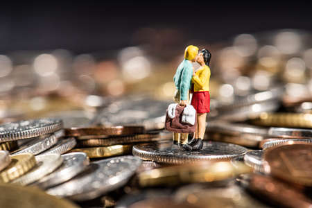 Small figures of a gouple kissing standing on a pile of coins.