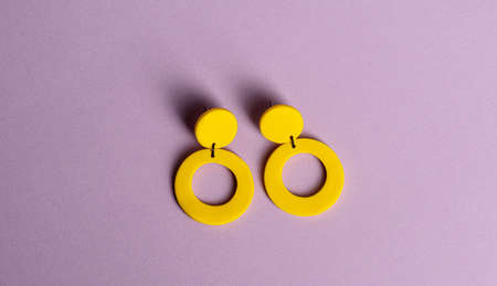 Yellow earrings on purple background.の写真素材