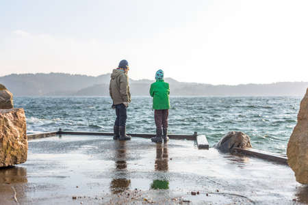 Two kids on a dock on a stormy day.の写真素材