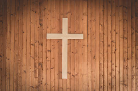 A christian cross in wood on a wall inside a church.の写真素材