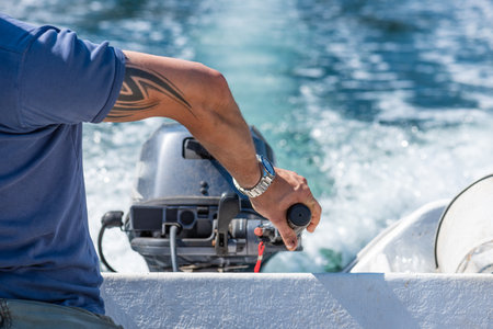 GÃ¶teborg, Sweden - July 23 2019: A hand steering an outboard engine on a white plastic boat.のeditorial素材