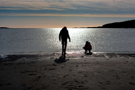 Silhouette of two persons on a sunny and sandy beach.