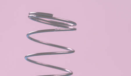 Details of a metal spring on pink cloth.