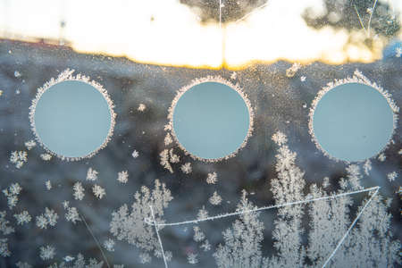 Ice crystals forming on a glass wall with round decalsの写真素材