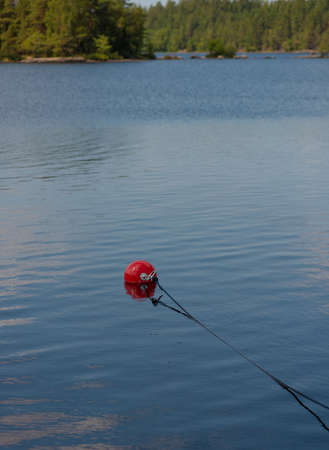 A red bouy used for mooring small boats in a lake.の写真素材