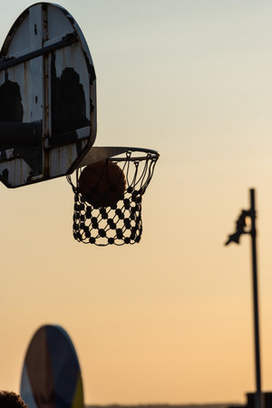 Basketball through hoop in golden sunset lightの写真素材