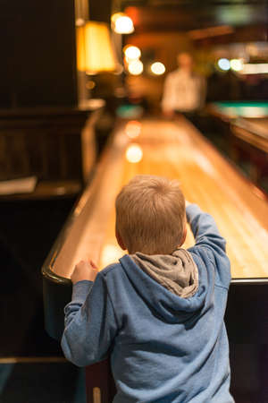 Young kid in blue hoodie playing shuffleboard..の写真素材