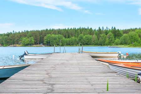 Wooden pier at a lake. Small boats on each side of the pier.の写真素材