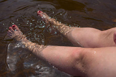 Woman legs stretching into cold water.の写真素材