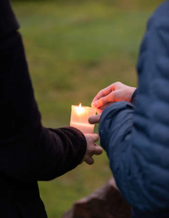 Grave candle being lit by two persons..の写真素材