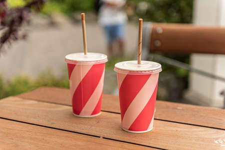 Two pink cups of soft drink with paper straws on a tableの写真素材