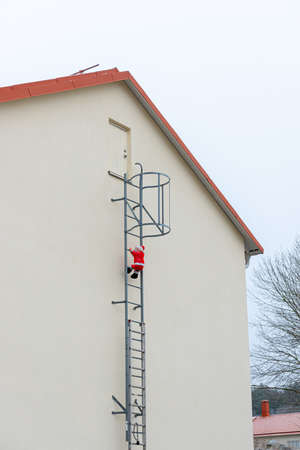 Christmas decoration on the side of a house. Inflatable Santa Clause climbing up a ladder..の写真素材
