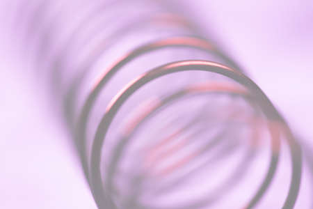 Details of a metal spring on pink cloth.