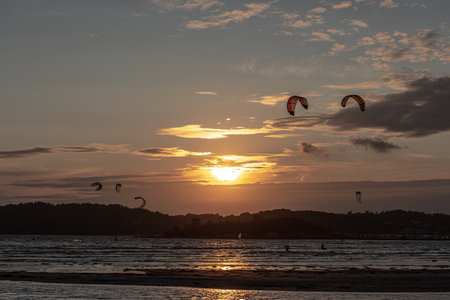 Gothenburg, Sweden - October 10 2021: Kiteboarders kitesurfing in the sunset by a beachのeditorial素材
