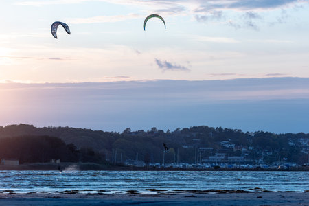 Gothenburg, Sweden - October 10 2021: Kiteboarders kitesurfing in the sunset by a beachのeditorial素材
