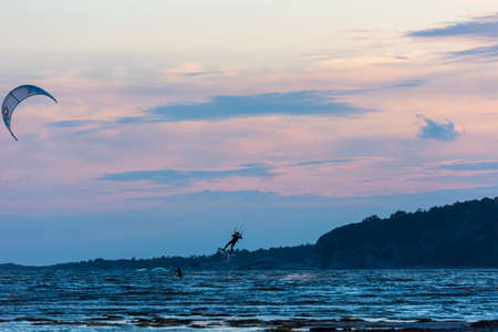 Kiteboarders kitesurfing in the sunset by a beach