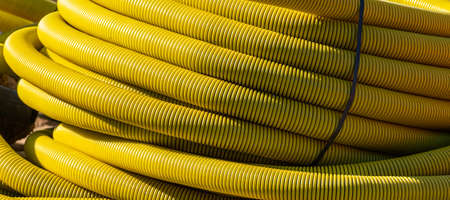 Large roll of yellow flexible pipe at a building site.
