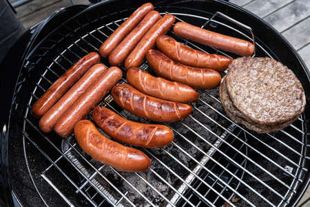 Hot dogs and hamburgers on a coal barbeque.