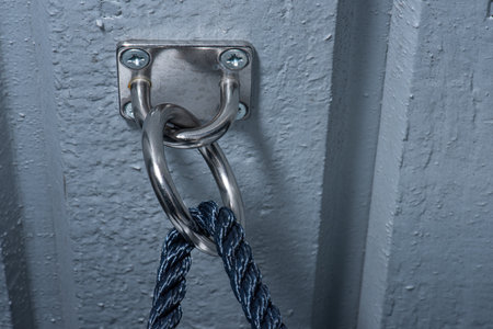 Blue rope going through a stowage bracket ojn a wall.