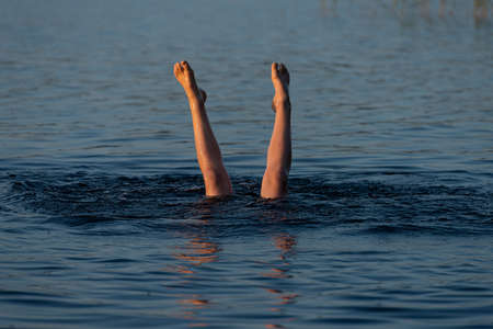 A person standing upside down in a lake. Legs visible over water.