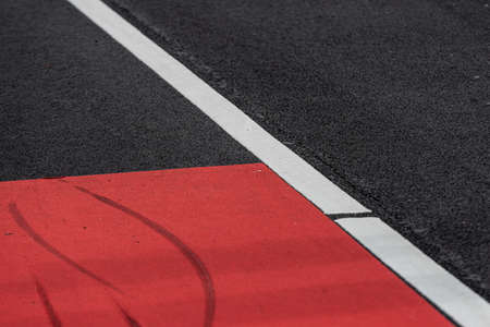 Asphalt decorated with a white line and a red field.の写真素材
