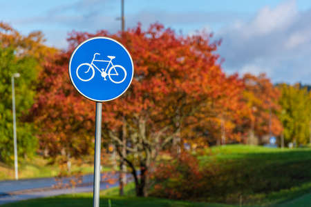 Bicycle path sign with autumn trees in the background.の写真素材