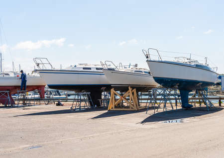 Sail boats laid up on a parking lot getting ready for the season.