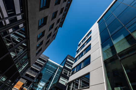 Looking up tall and modern office buildings in concrete glass and steel.の写真素材