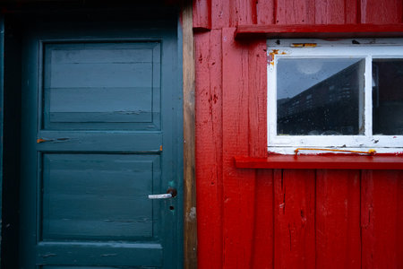 Old wooden blue door and red wall with a small windowの写真素材
