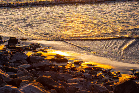 Wawes on a small beach at a golden sunsetの写真素材