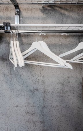 White clothes hangers on a rack with concrete wall behindの写真素材