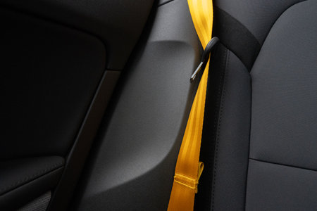 Golden yellow seat belt in a dark grey car interior