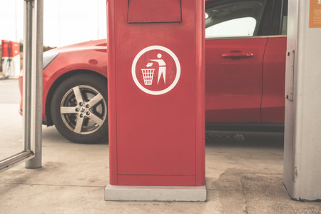 Red litter box by a red car at a gas station