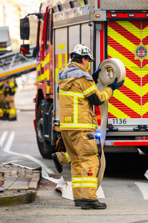 Gothenburg, Sweden - February 25 2023: Firefighter rolling a hose after putting out a fire