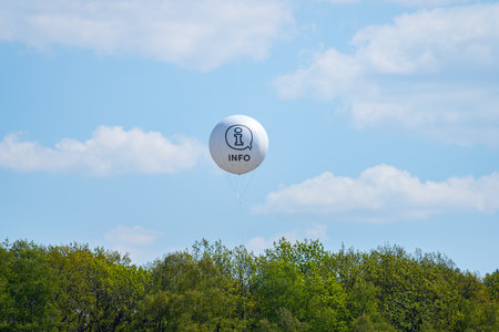White helium balloon over trees marked Infoの写真素材