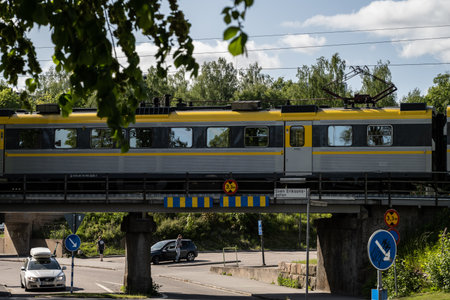 BorÃ¥s, Sweden - May 28 2023: Local train on a low overpass over car trafficのeditorial素材