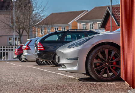 Gothenburg, Sweden - March 16 2021: Front of a Tesla Model 3 lokking out from behind a red building.のeditorial素材