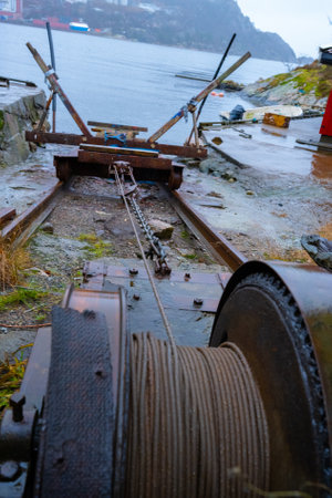 Old rusty winch with metal cable pulling a slip by the seaの写真素材