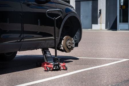 Gothenburg, Sweden - July 08 2023: Car lift holding up a black car missing a front wheel on a...