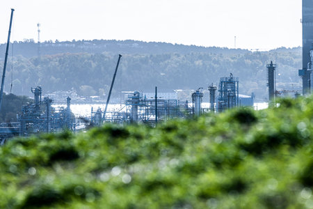 Equipment at an oil refinery behind grass hillの写真素材
