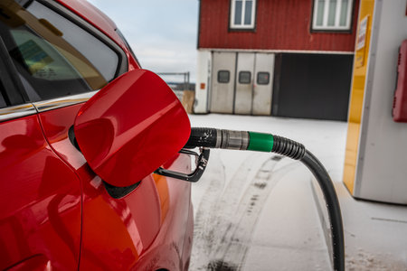 Red car filling up with gasoline on a cold winter day