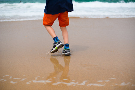Kid in orange shorts playing on a beachの写真素材