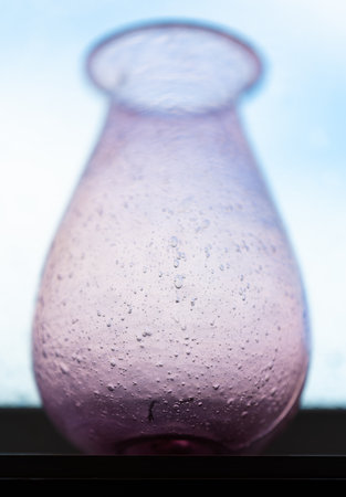 Purple hand made glass vase in a windowの写真素材