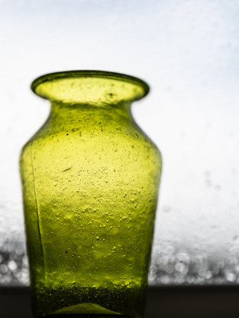 Green hand made glass vase in a windowの写真素材
